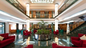 A spacious lobby with a central planter, red seating, and a staircase. - Elba Vecindario Aeropuerto Business & Convention Hotel (Santa Lucia)