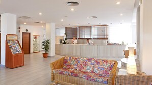 Una zona de recepción con un mostrador de madera, un sofá de mimbre y una barra de recepción.