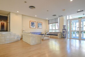 A spacious lobby with a staircase, two sofas, a coffee table, and a large vase. - Club Hotel Cala Ratjada (Capdepera)