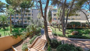 Un edificio de varios pisos con balcones, rodeado de abundante vegetación y árboles.