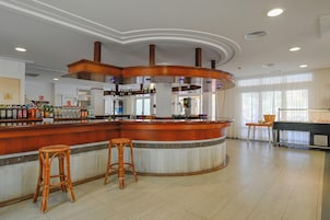 Una zona de bar con taburetes, mostrador y una variedad de botellas.