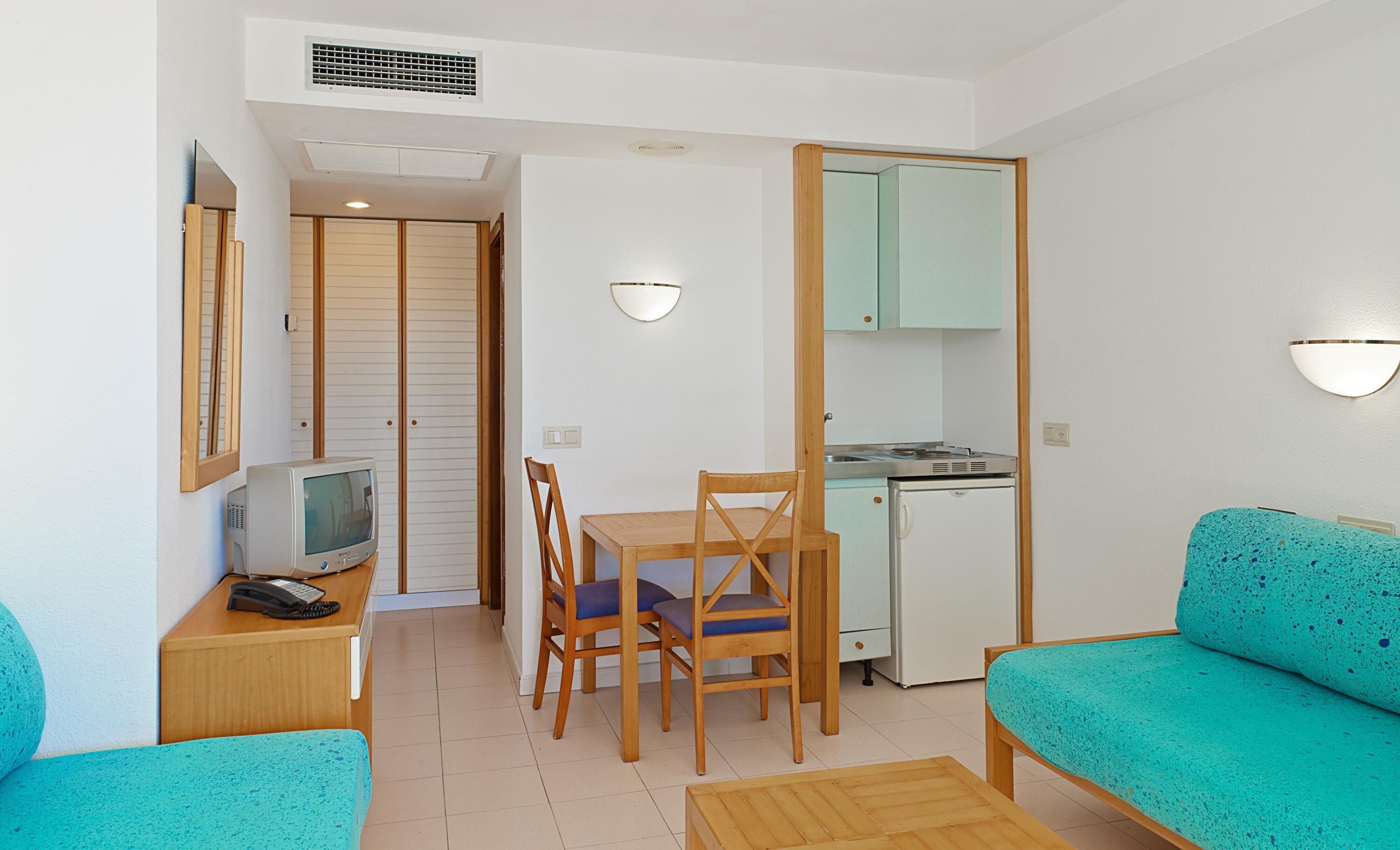 Un espacio habitable compacto con comedor, kitchenette, televisor y sofá.