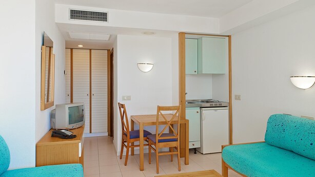 Un espacio habitable compacto con comedor, kitchenette, televisor y sofá.