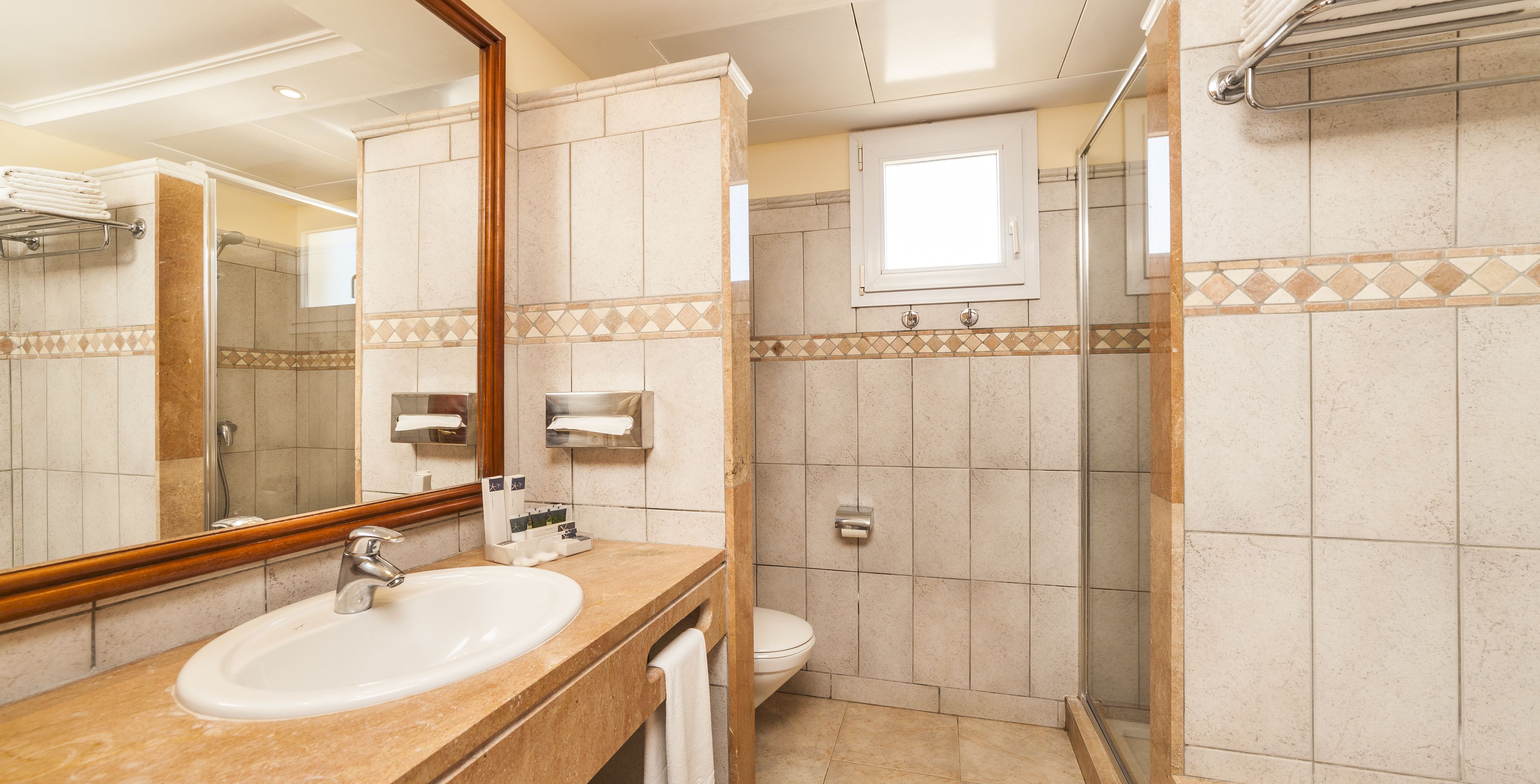 Un baño con lavamanos, espejo, inodoro y ducha.