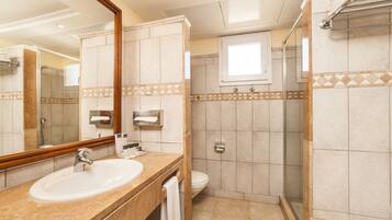 Un baño con lavamanos, espejo, inodoro y ducha.