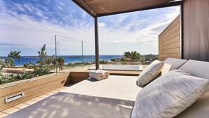 A modern balcony with a view of the sea, a sofa with cushions, and a wooden wall. - Insotel Punta Prima Resort & Spa (Sant Lluis)