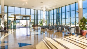 A spacious lobby with a reception desk, seating area, and large windows offering views of the outdoors. - Insotel Punta Prima Resort & Spa (Sant Lluis)