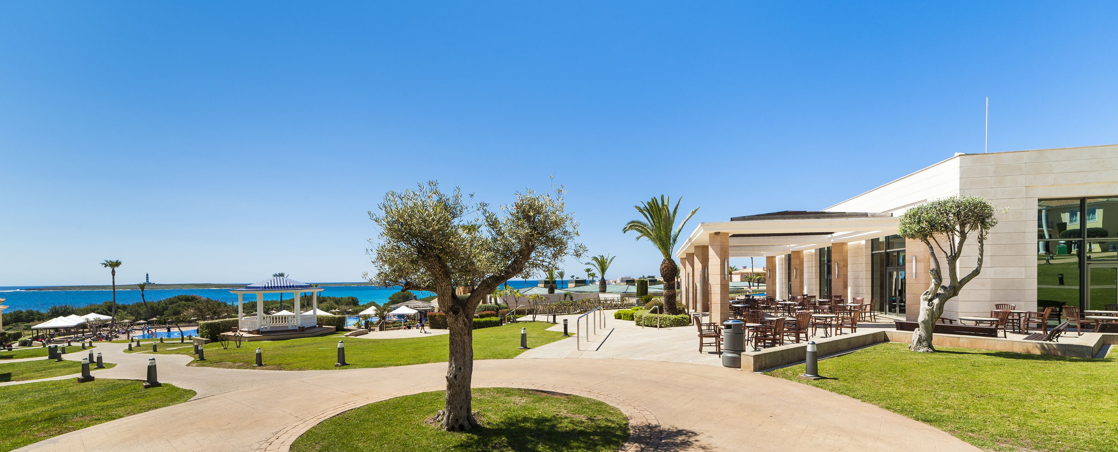 Un resort con asientos al aire libre, piscina y vista al mar.