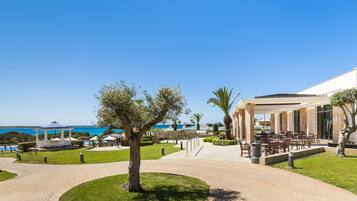 Un resort con asientos al aire libre, piscina y vista al mar.