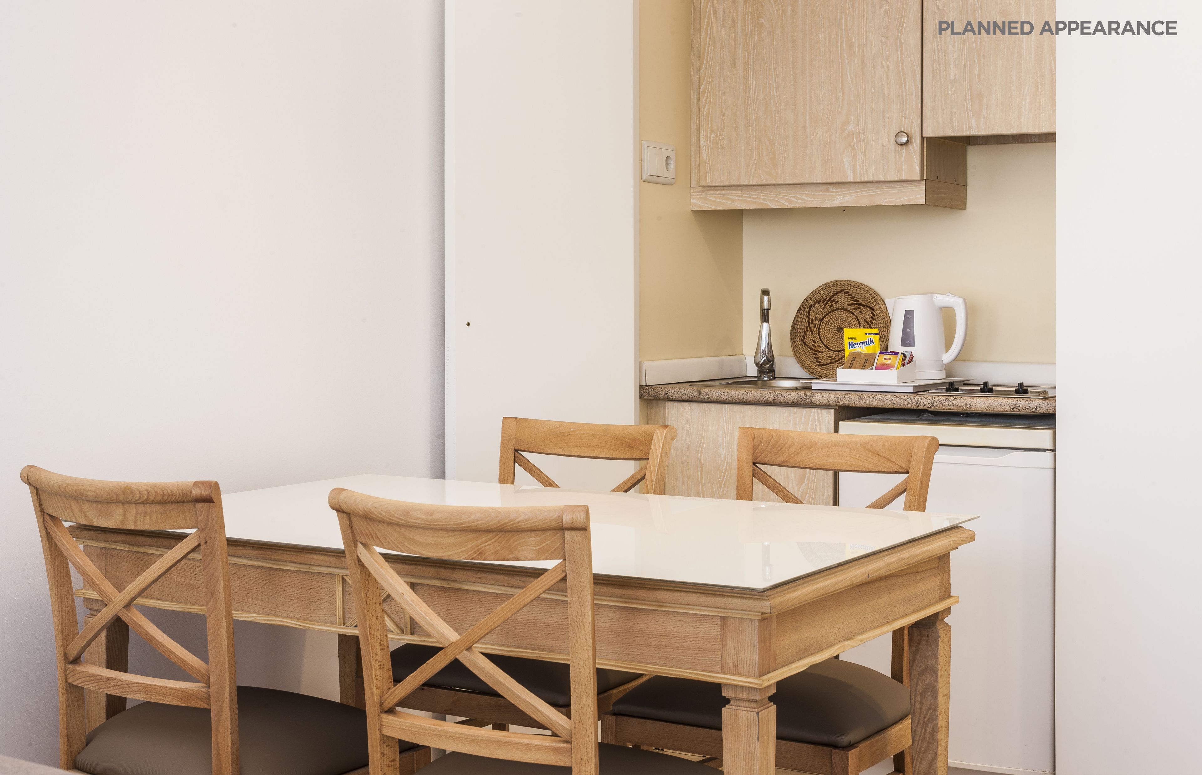 Uma cozinha compacta com mesa e cadeiras, chaleira e cafeteira.