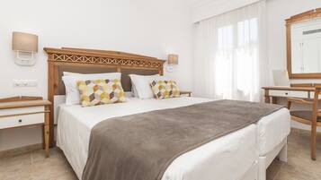 Una habitación de hotel con cama, mesitas de noche, un espejo y una ventana con cortinas.