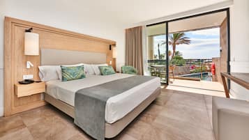 Ein Hotelzimmer mit Bett, Nachttisch und Blick auf einen Pool und Palmen.