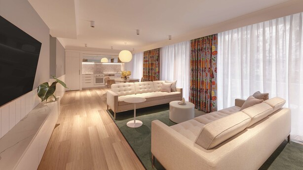 A modern living room with a sofa, coffee table, and TV. There is a kitchen in the background with a dining area.