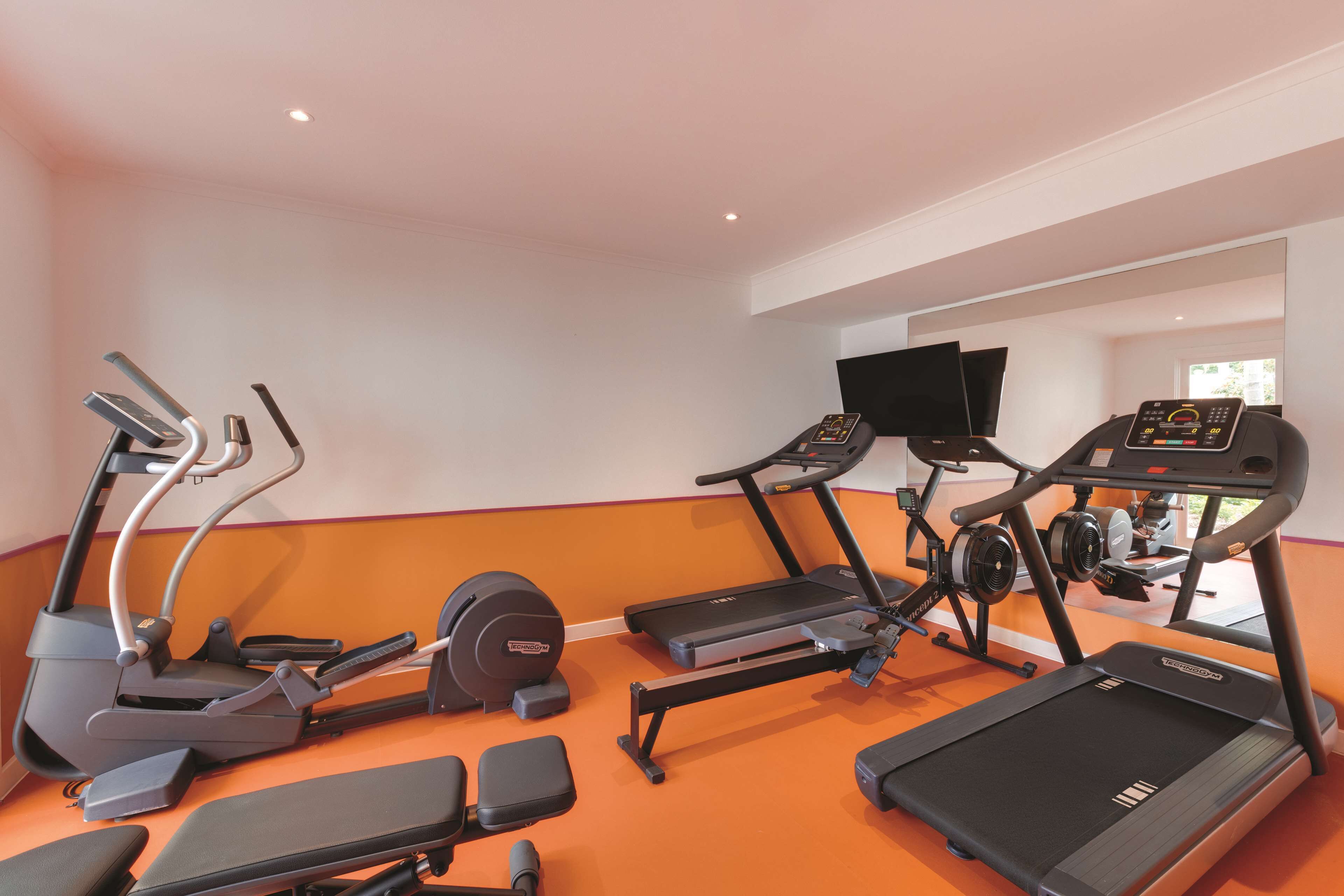 Et fitnesscenter med løbebånd, crosstrainere og styrkemaskiner.