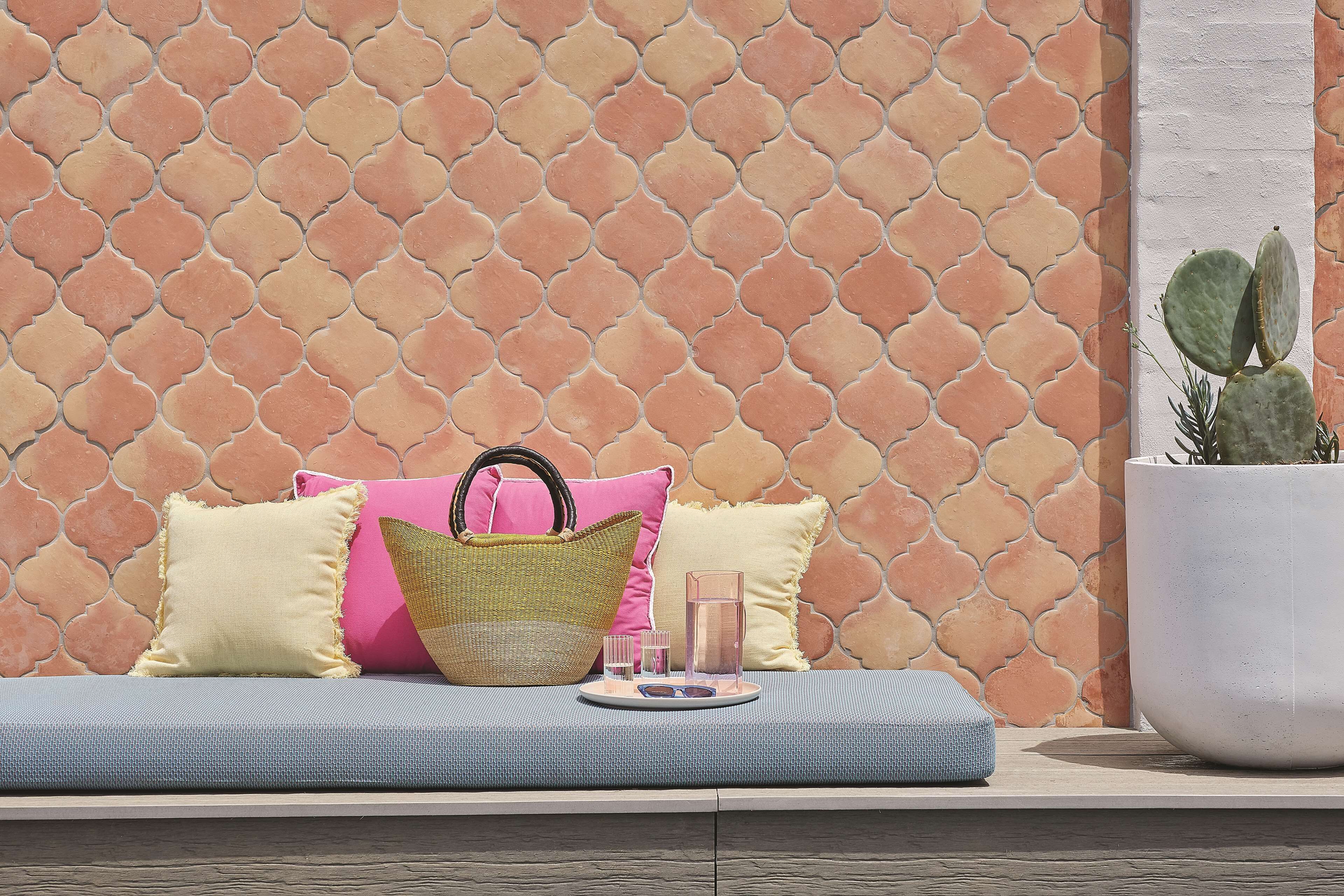 A seating area with a patterned wall, a large potted plant, and a basket.