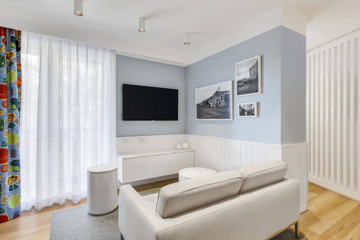 Un salon moderne avec un téléviseur à écran plat, un canapé blanc et une petite table ronde.