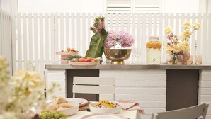 A dining table set with various fruits, vegetables, and a decorative centerpiece.