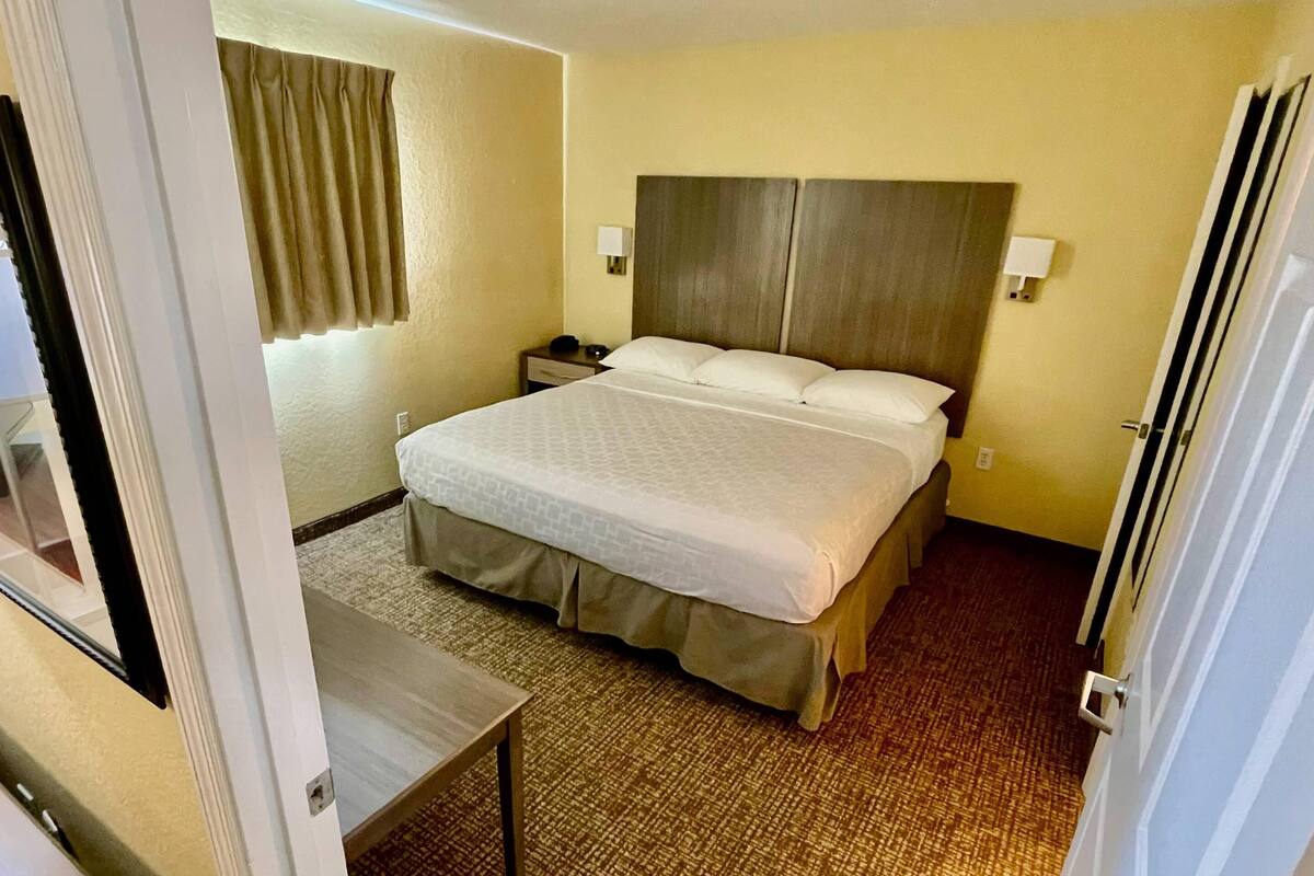 Ein Hotelzimmer mit einem großen Bett, Nachttischen und einem Fenster mit Vorhängen.