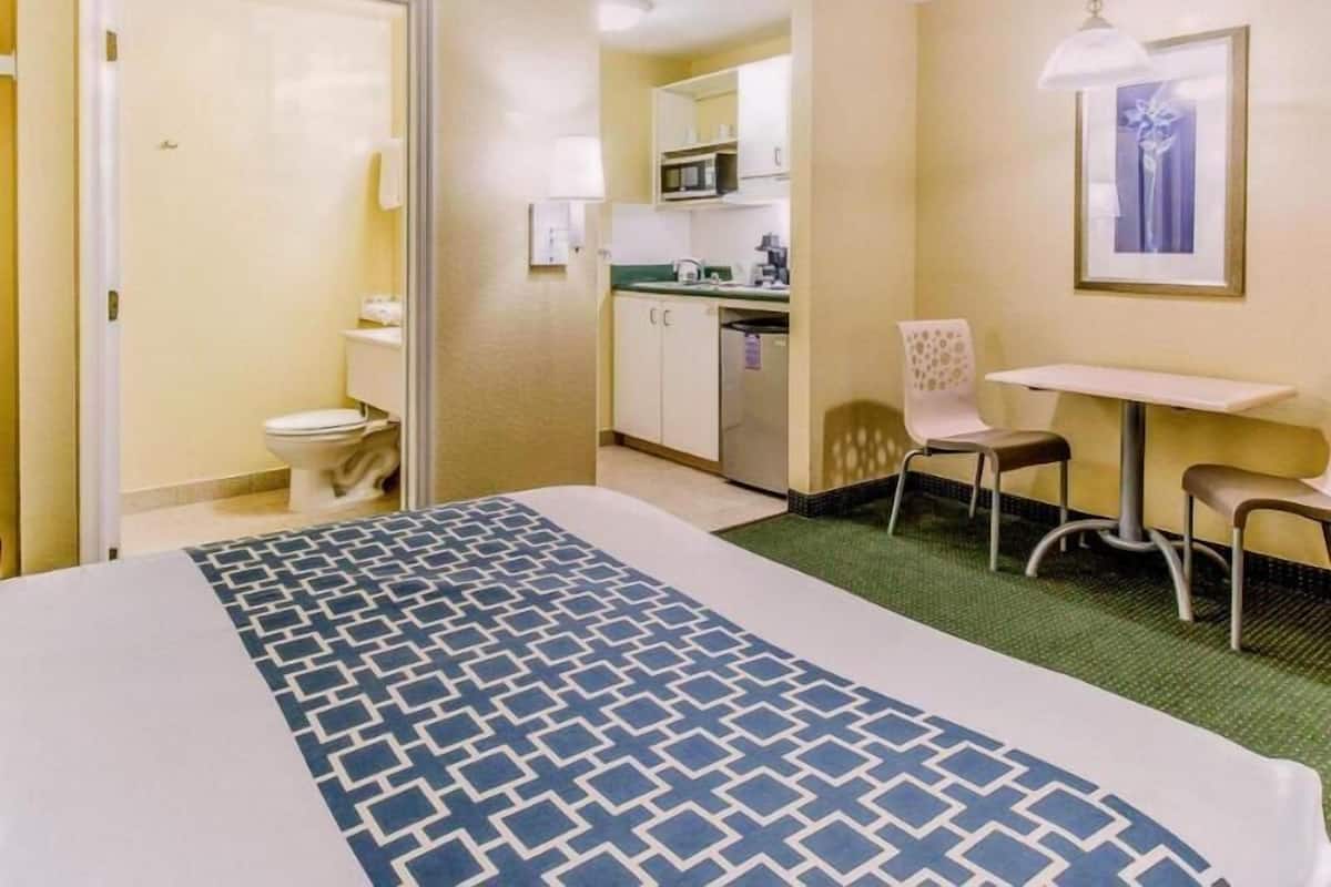 Ein Hotelzimmer mit Bett, Küchenzeile, Bad und einer kleinen Essecke.