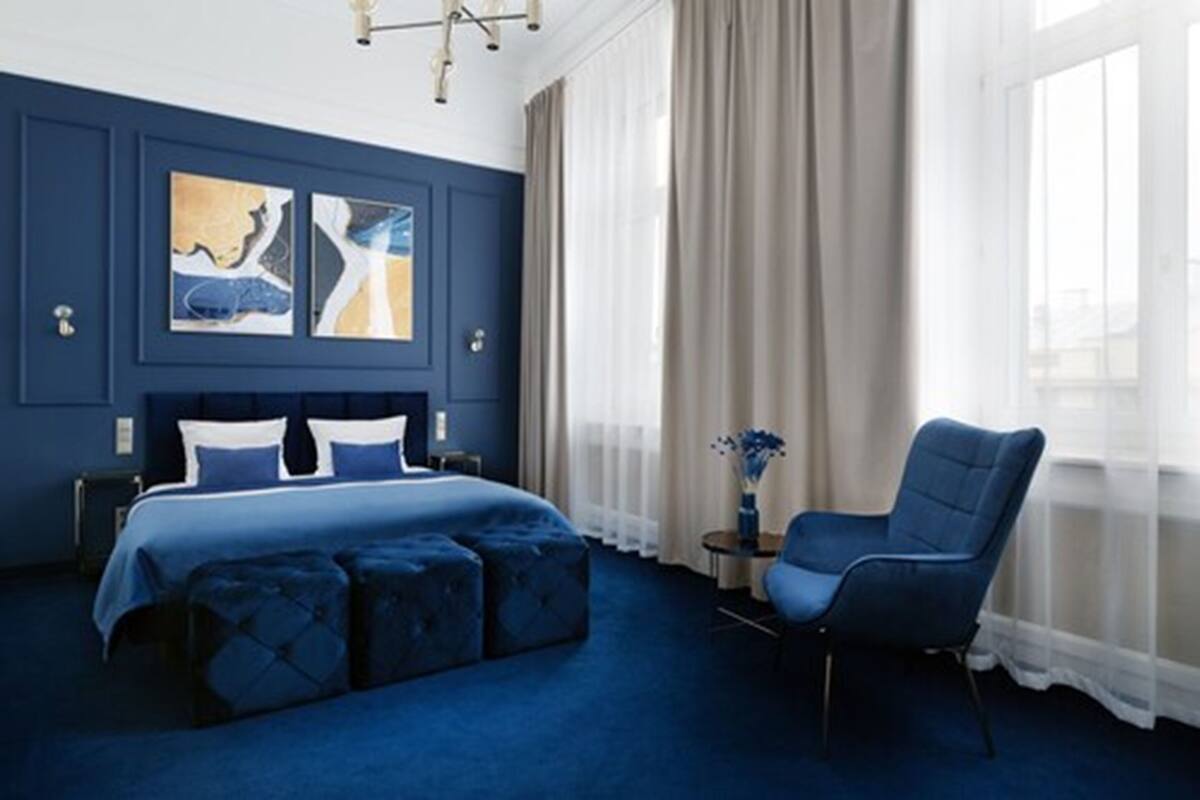 A bedroom with a large bed, a chair, and artwork on the wall.