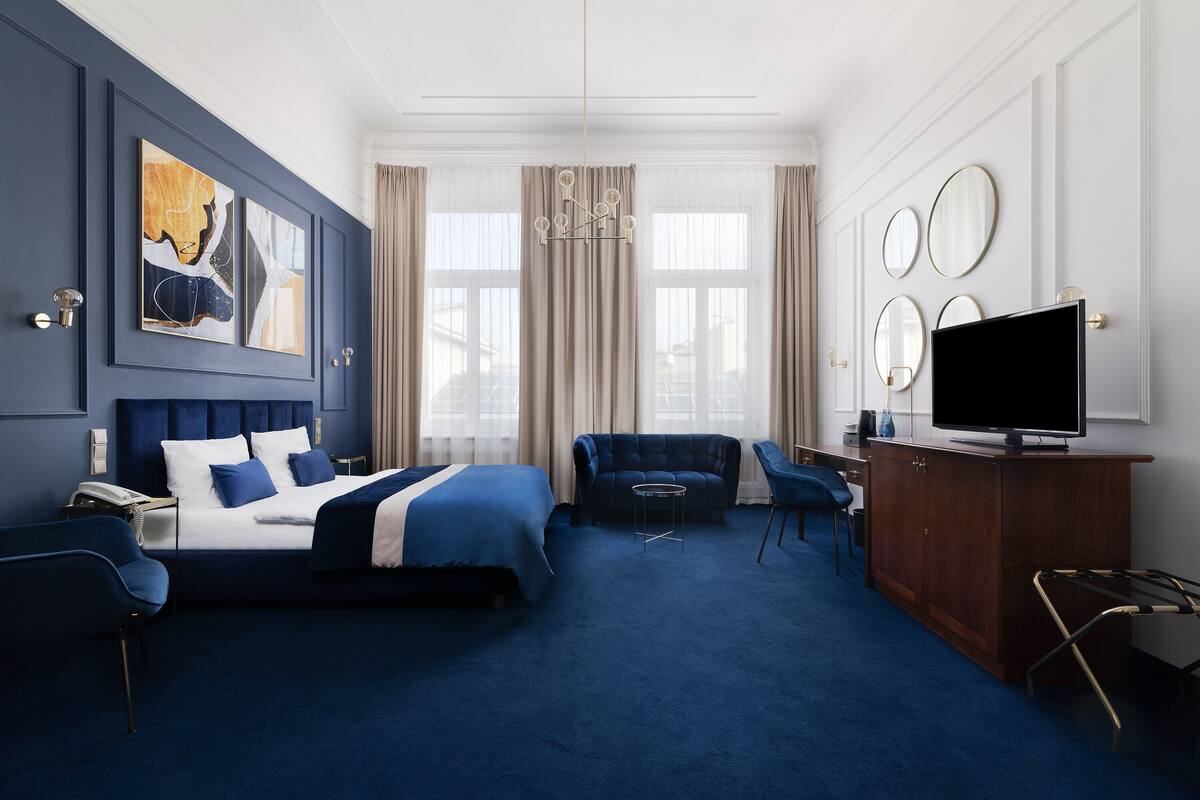 A hotel room with a large bed, a sofa, a TV, and a desk.