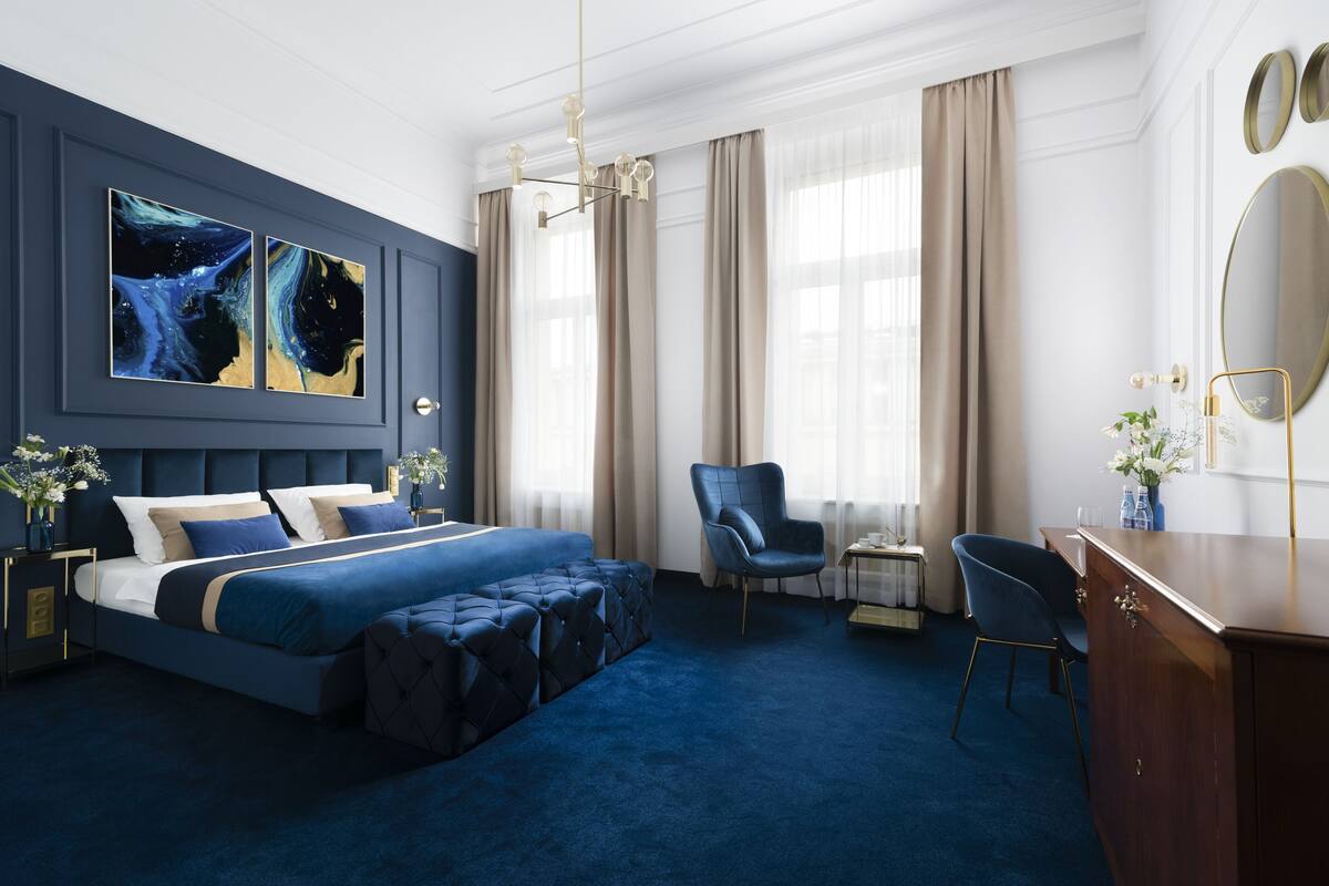 A modern hotel room with a large bed, a seating area, and a desk.