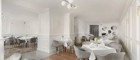 Un vaste espace dédié à la salle à manger, avec de nombreuses tables et chaises, de beaux luminaires au plafond et un style architectural classique.