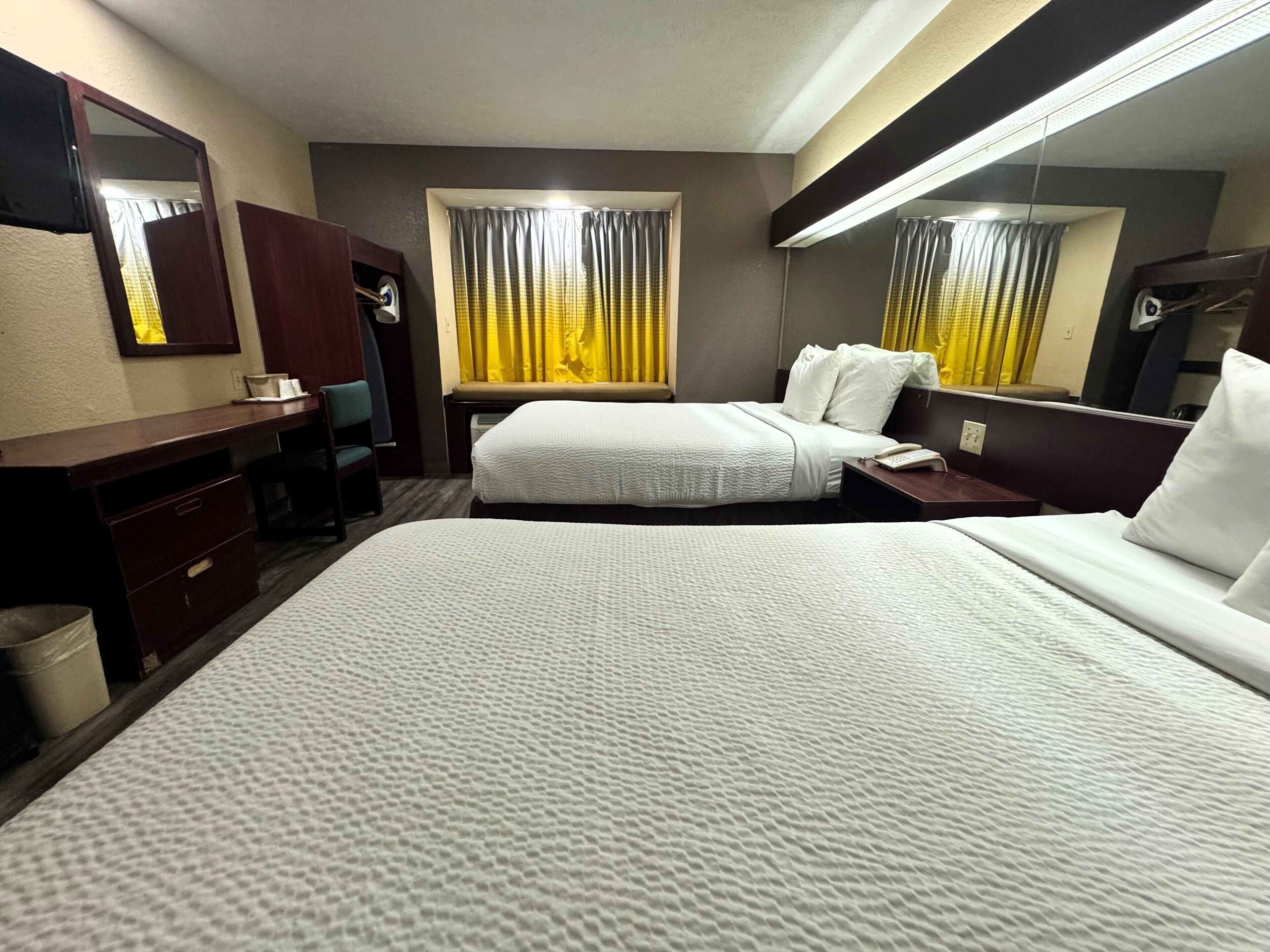 Una habitación de hotel con una cama grande, un escritorio, una silla, una mesita y un espejo.