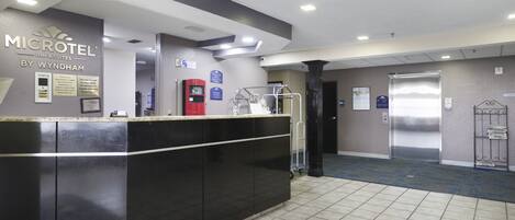 A reception area with a black counter, a red self-service kiosk, and a blue sign indicating a parking area.