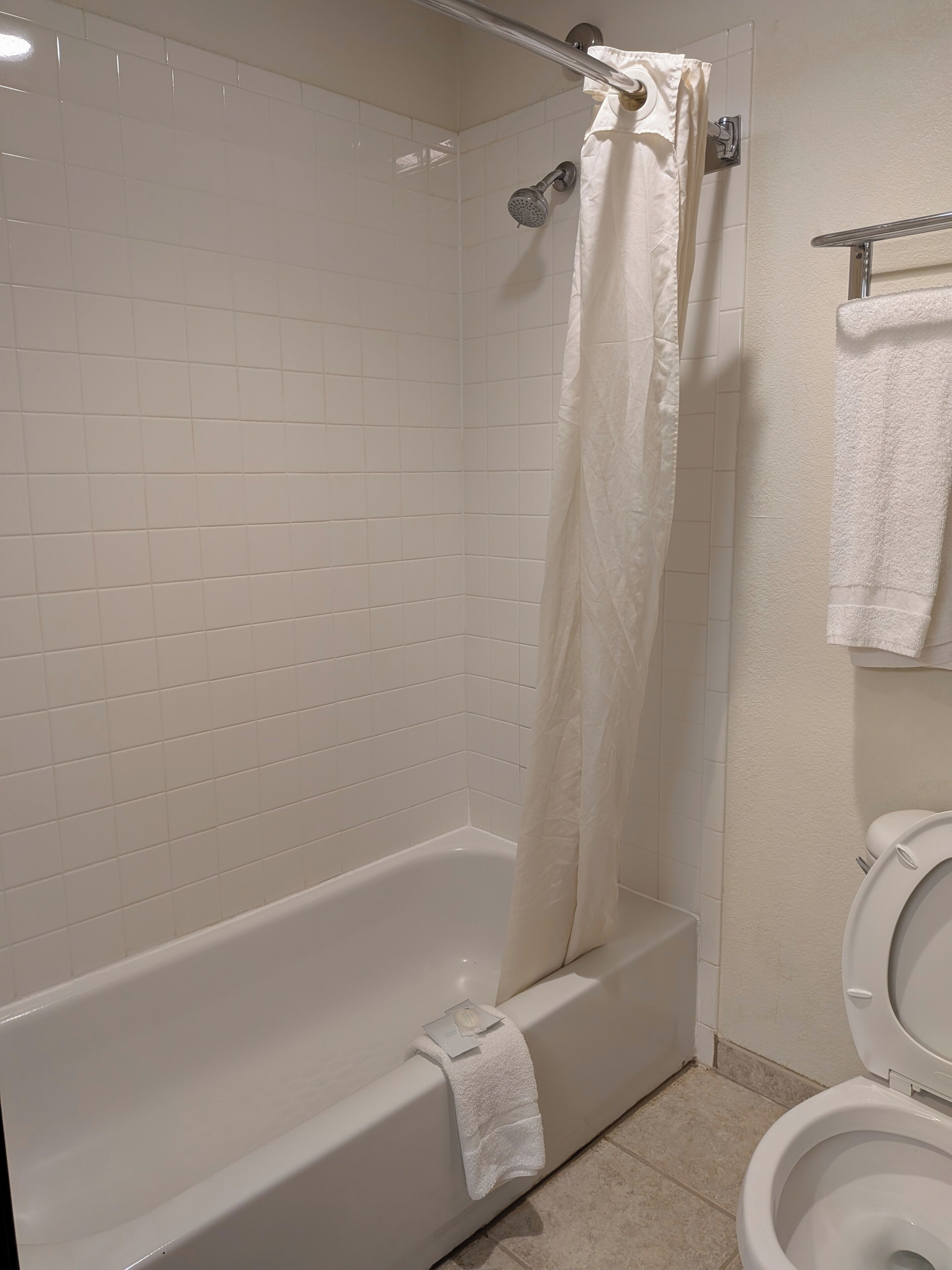 A bathroom with a white bathtub, a shower curtain, and a toilet.