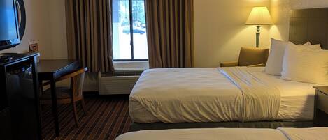 Une chambre d’hôtel avec deux lits, un bureau, une télévision et une fenêtre avec des rideaux.