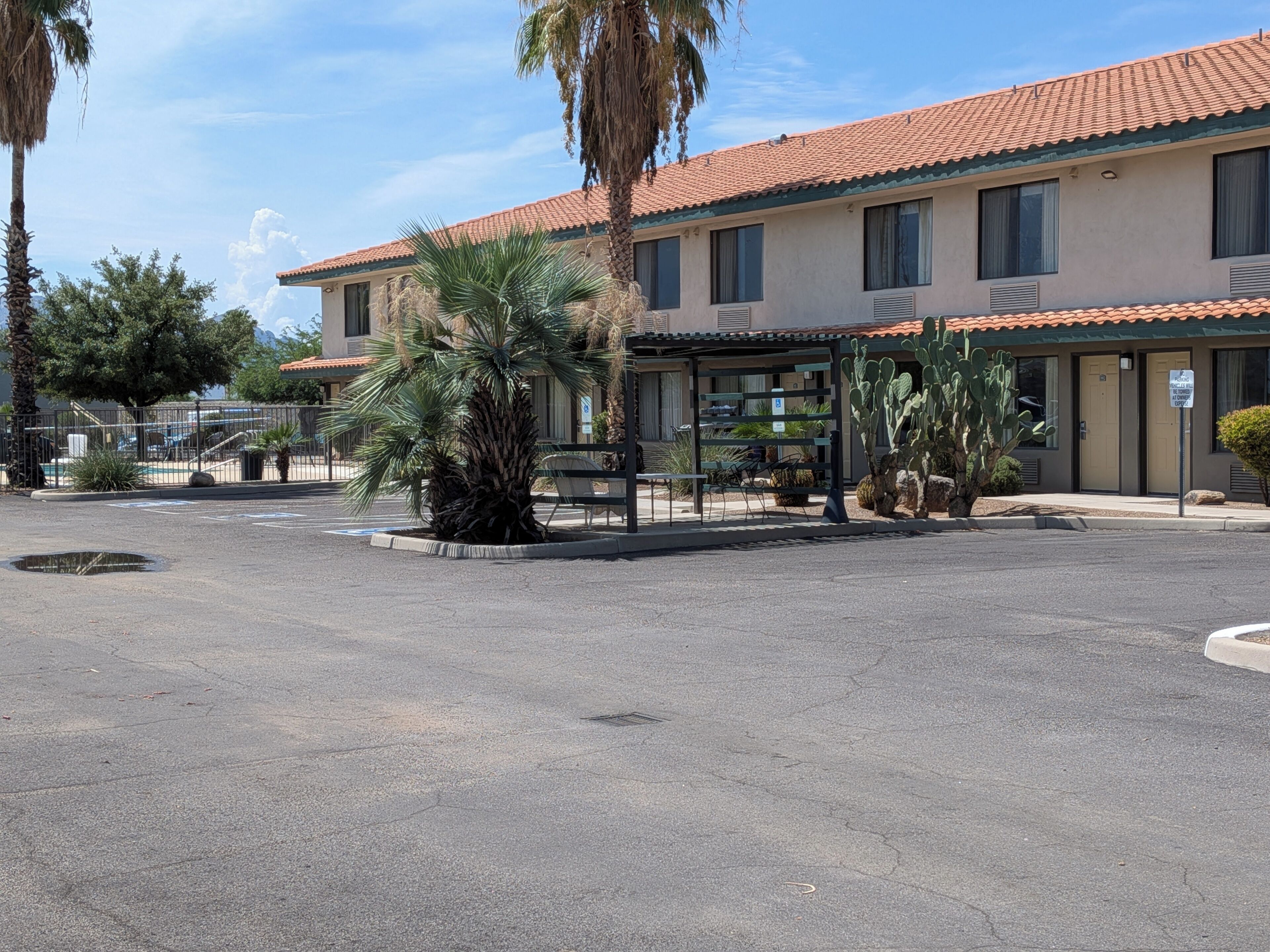 A building with a tiled roof, a parking lot, and a palm tree.