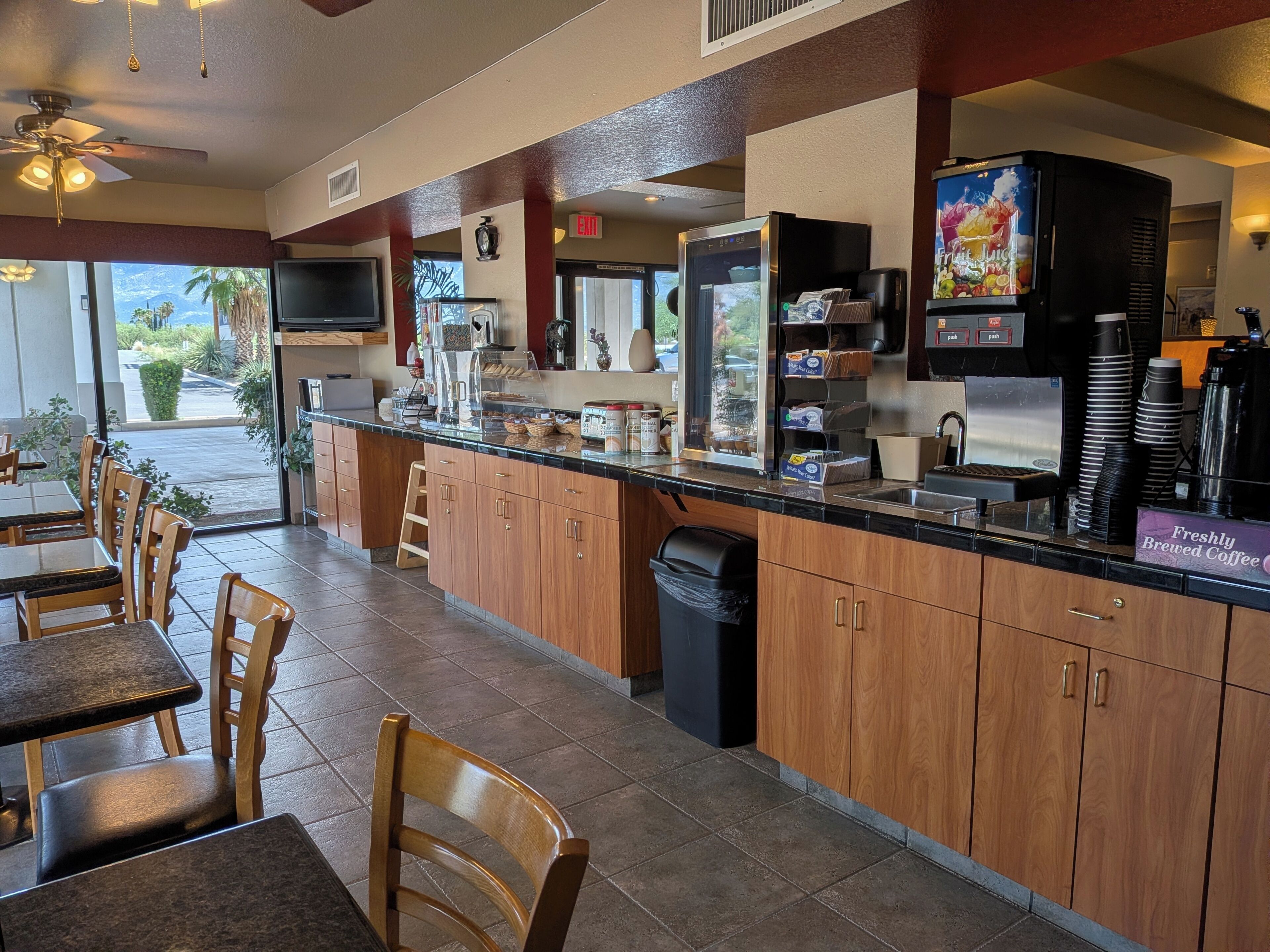 A restaurant with a counter, seating area, and a view of the outdoors.