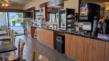 A restaurant with a counter, seating area, and a view of the outdoors.