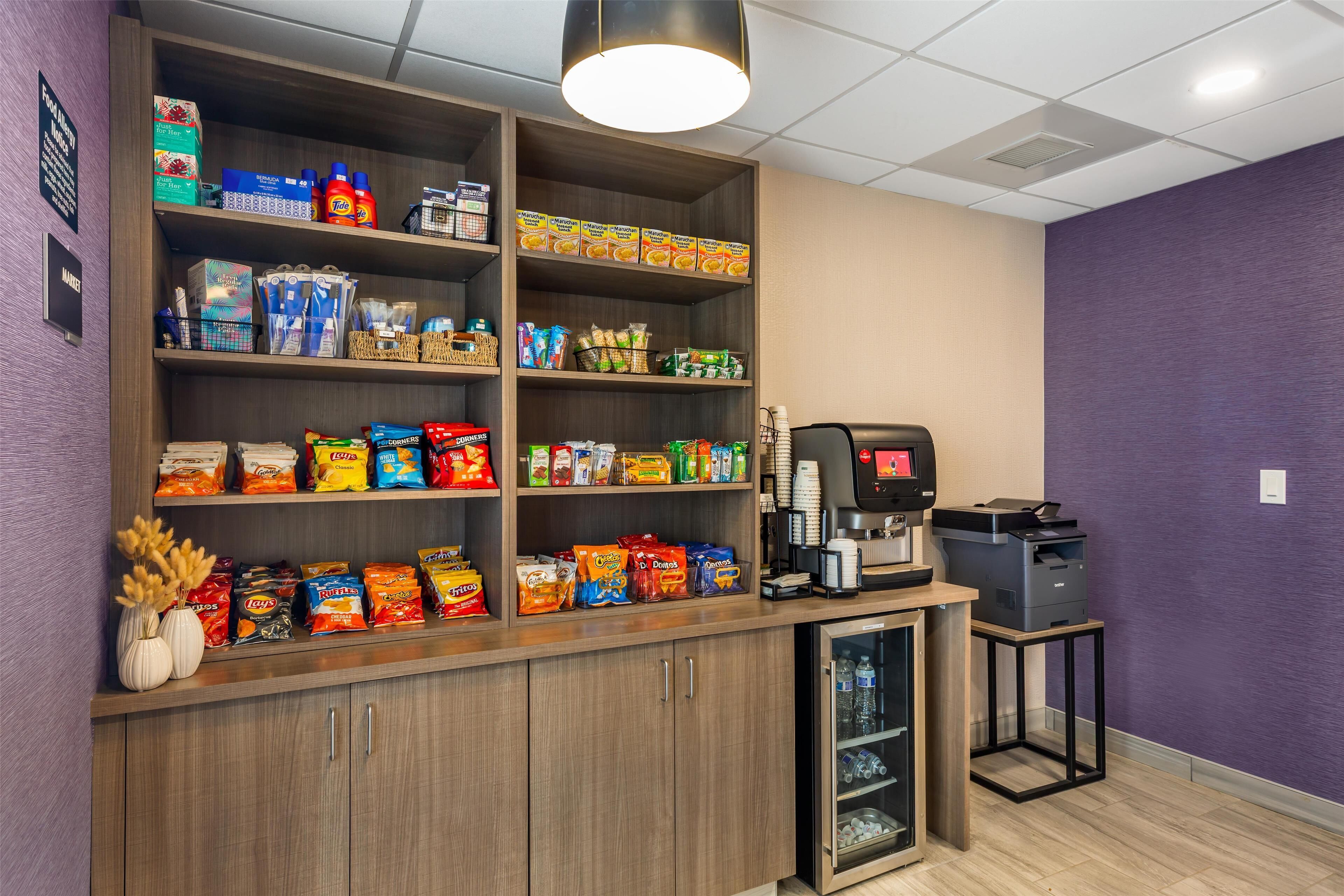 Una estación de bebidas de autoservicio con una cafetera y un refrigerador.