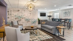 Un salon moderne avec un canapé gris, une table basse ronde et un tapis à motifs.