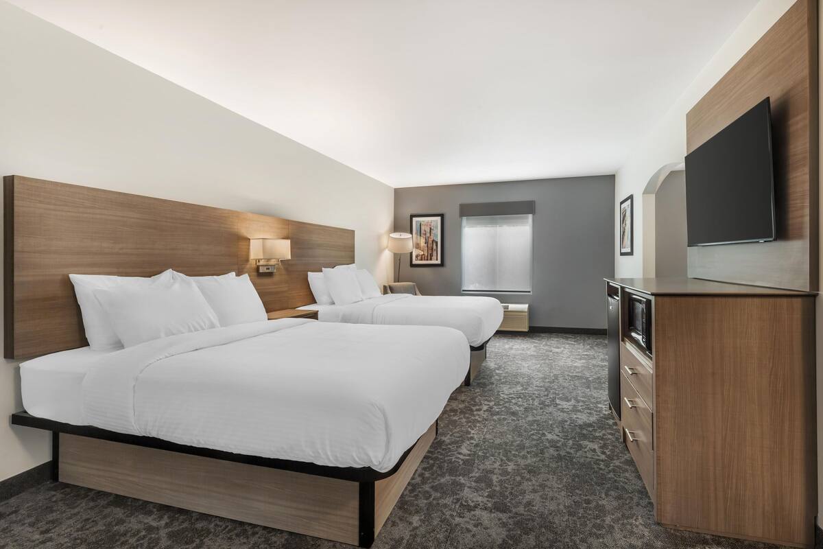 Una habitación de hotel con dos camas, televisión, escritorio y ventana.
