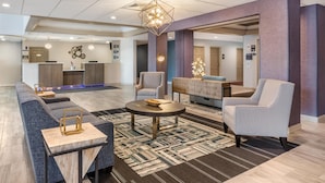 Um hall moderno com um sofá de canto, poltronas, uma mesa de centro e um balcão de recepção.