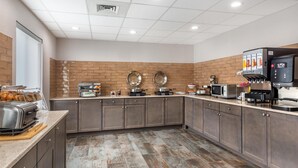 Une cuisine moderne avec un mur d’accent en briques, des appareils en acier inoxydable et une machine à café.