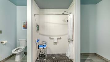 Un baño con ducha, inodoro y un banco accesible para silla de ruedas.