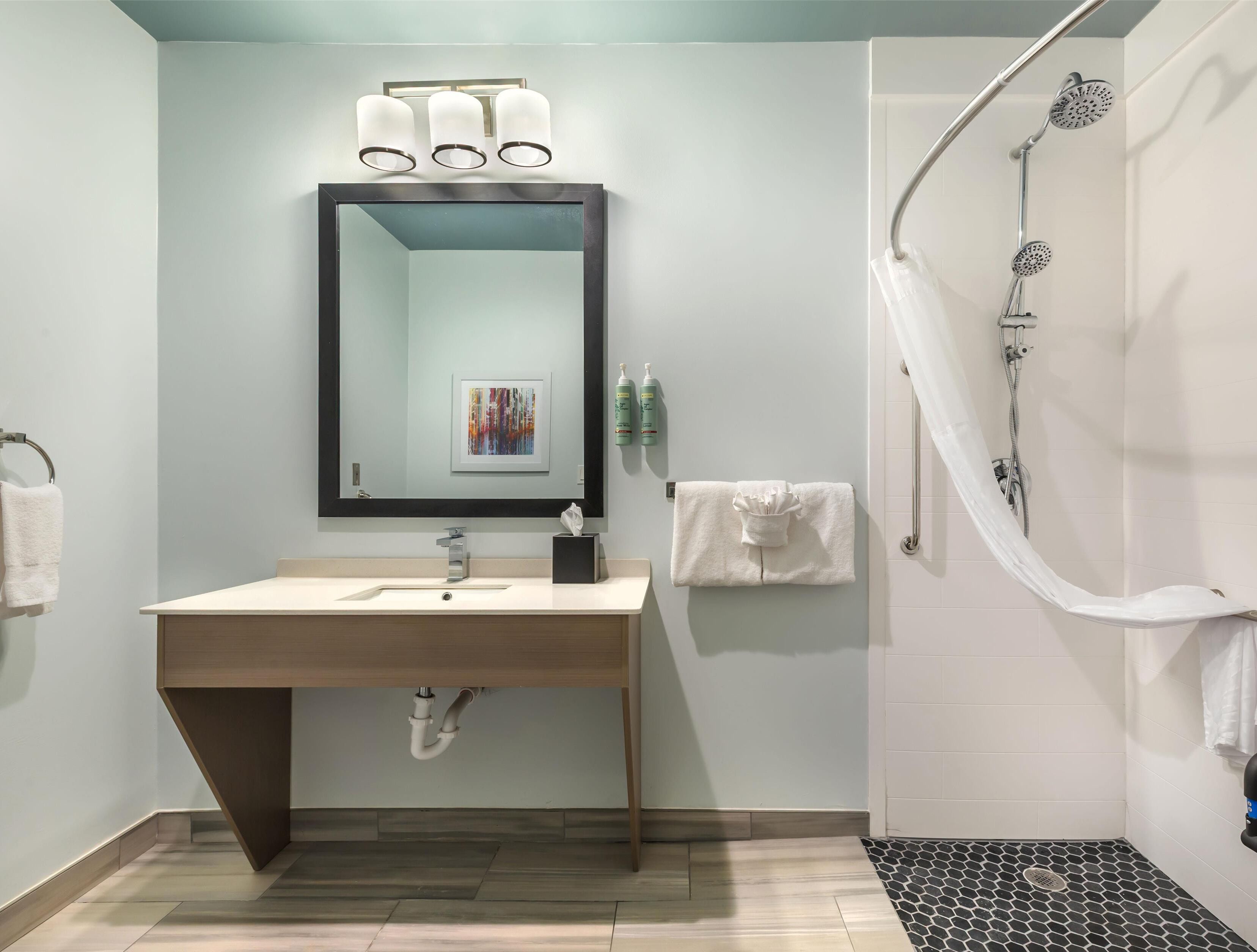 A modern bathroom with a sink, mirror, and shower.