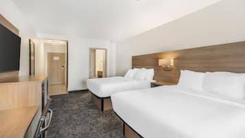 A hotel room with two beds, a desk, and a TV.