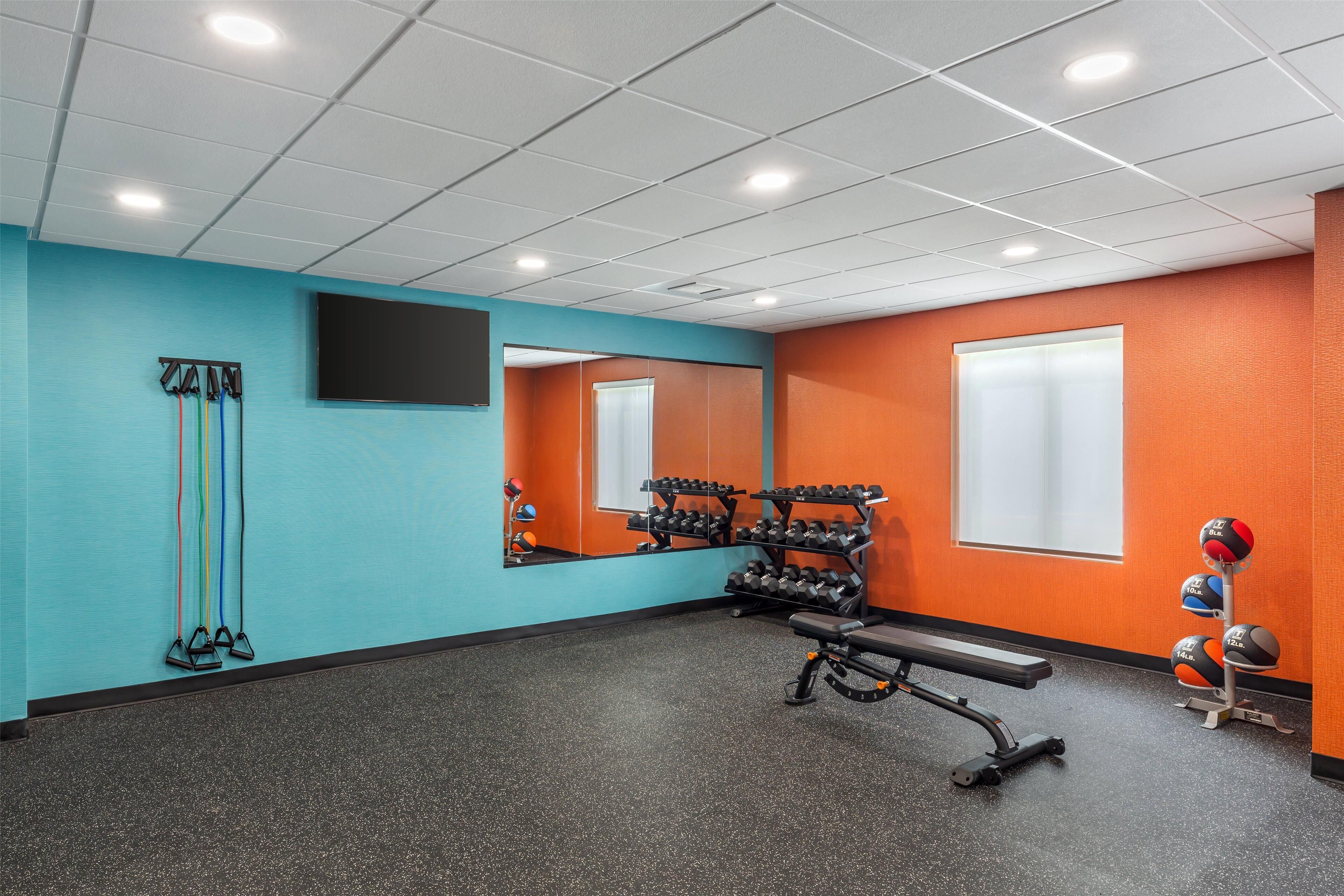 A gym with a mirrored wall, exercise equipment, and a bench.