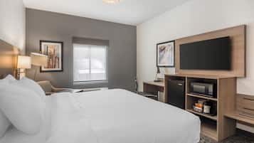 Habitación de hotel con una cama grande, un televisor de pantalla plana, un microondas y un escritorio con una silla.
