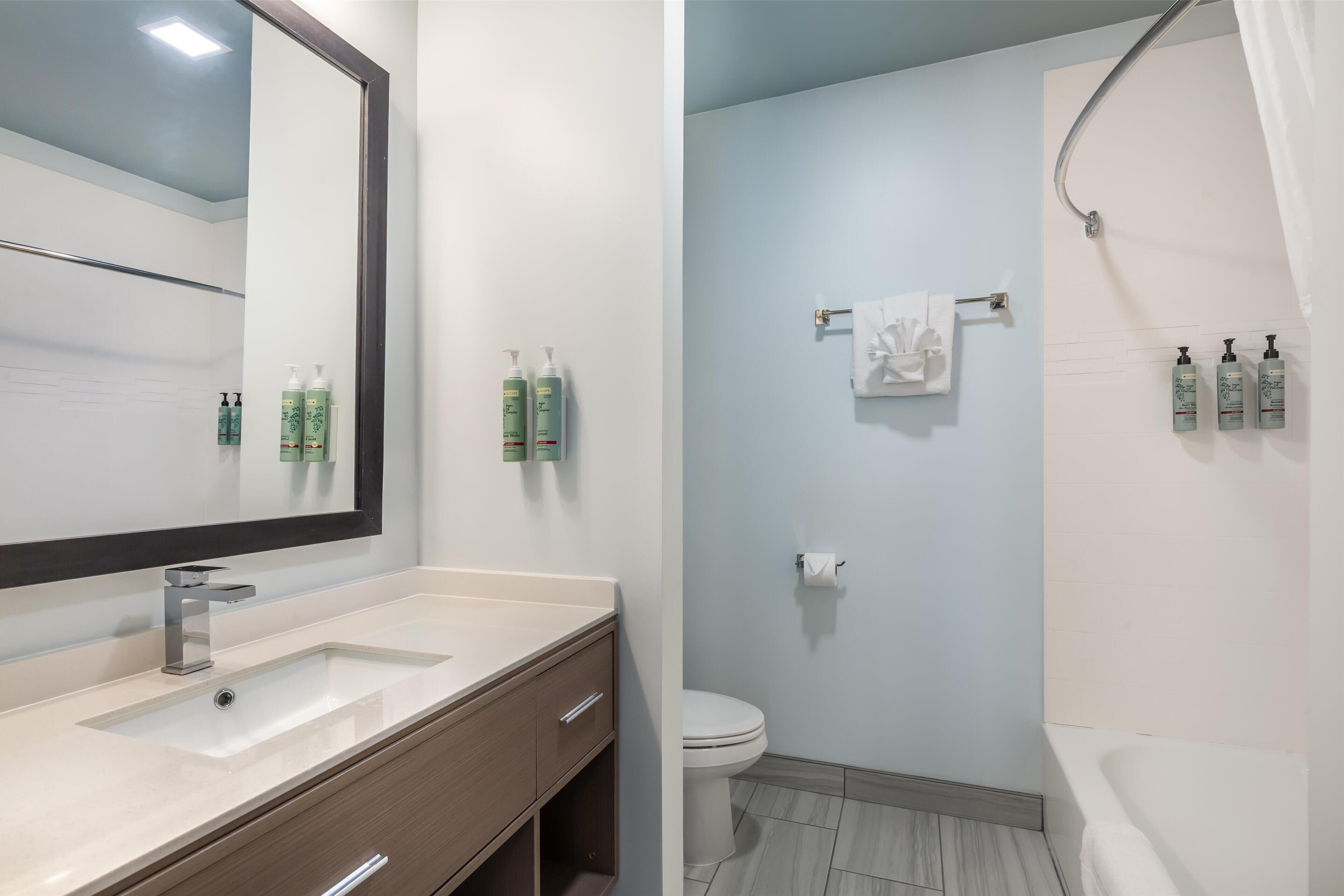A bathroom with a sink, mirror, and toiletries on the wall.