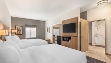 Quarto de hotel com duas camas, televisão, micro-ondas e porta para uma casa de banho.
