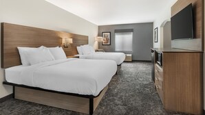 Une chambre d’hôtel avec deux lits, un bureau, un téléviseur à écran plat et une grande fenêtre.
