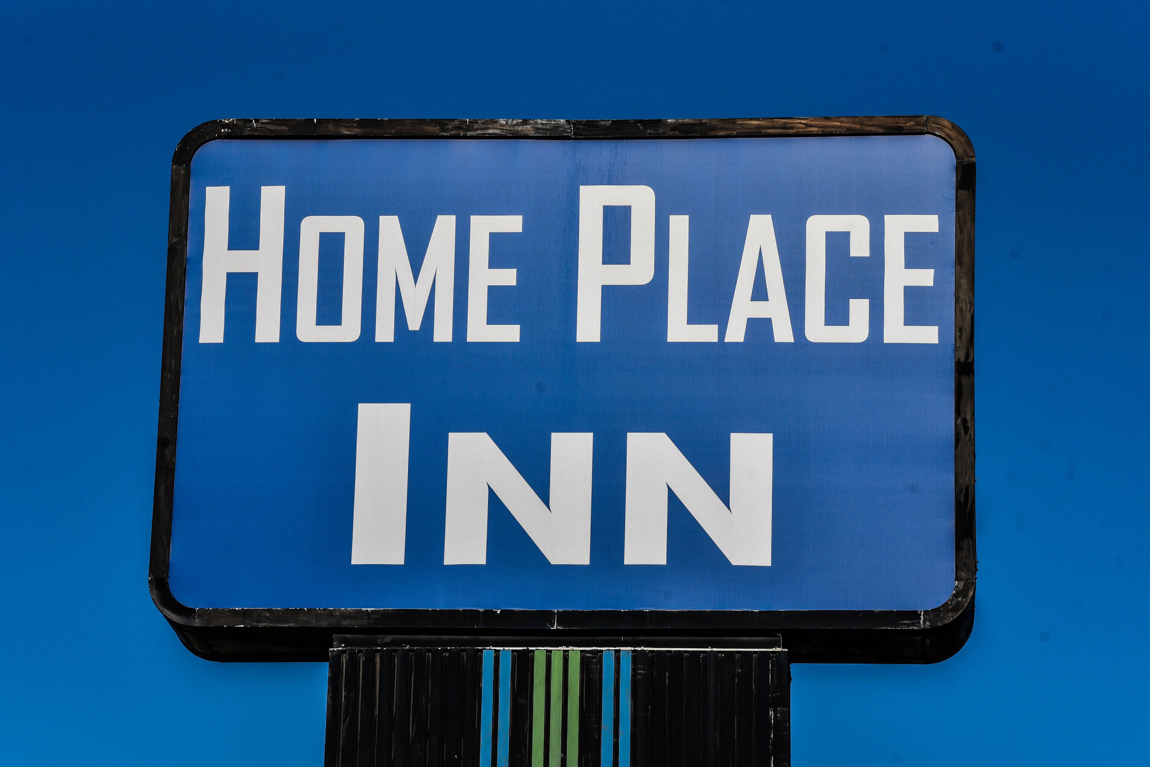 Un letrero azul con texto blanco que dice 'HOME PLACE INN'.