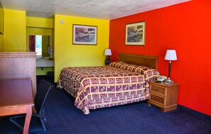 A hotel room with a bed, bedside lamps, a dresser, and a desk.