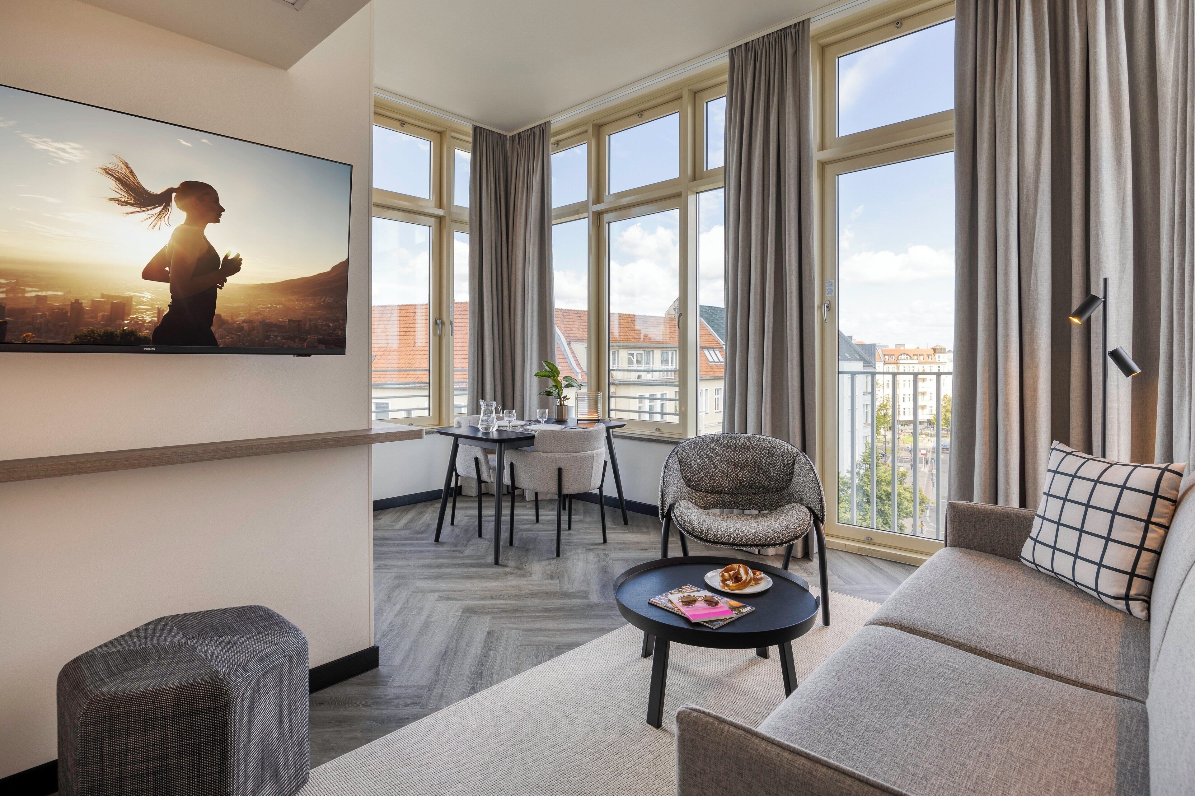 Ein modernes Wohnzimmer mit großem Fenster, einer Couch, einem kleinen Tisch und einem Sessel.